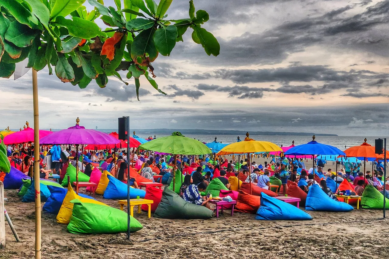 Sombrillas y pufs de colores en una playa de Bali bajo un cielo que se abre tras un chaparrón