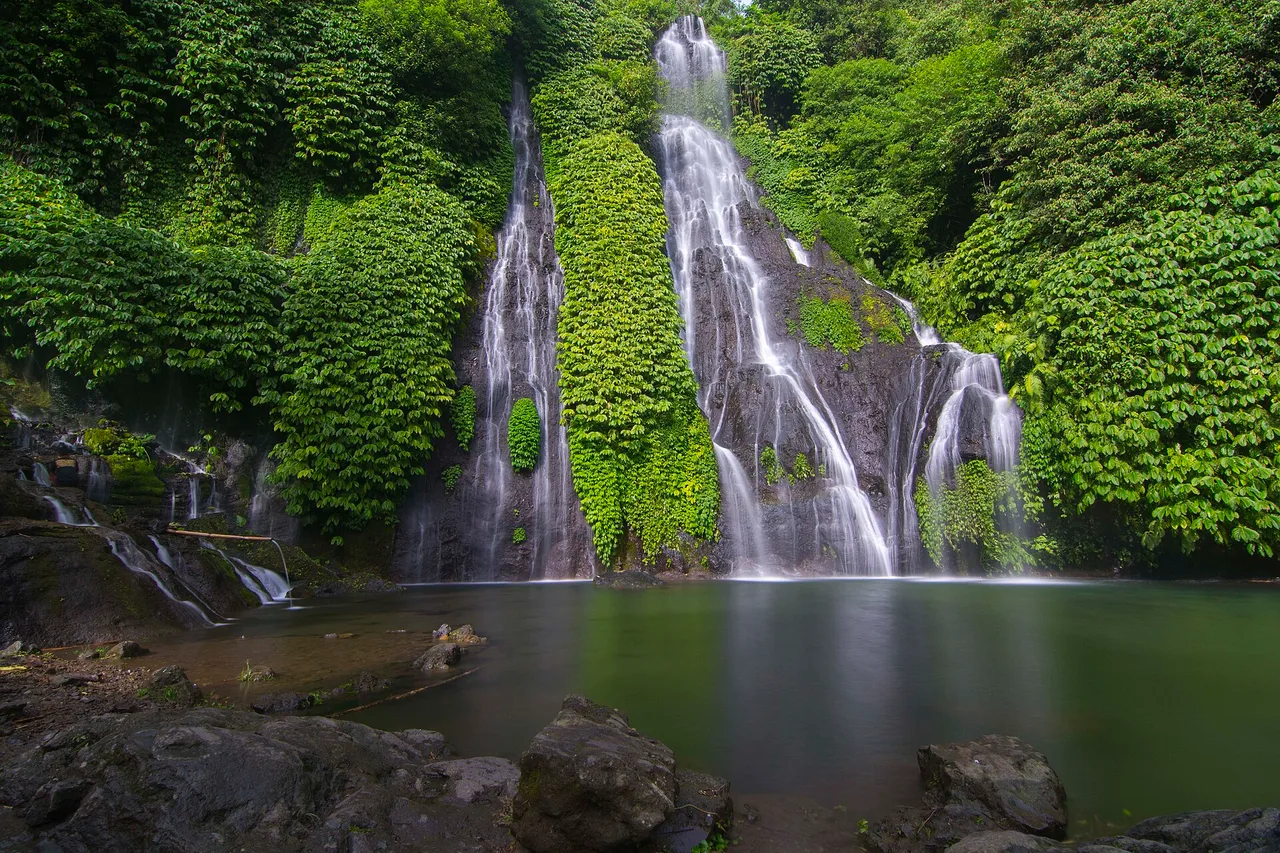 Le cascate gemelle di Banyumala su una parete vegetale, sotto un’ampia vasca calma, Bali