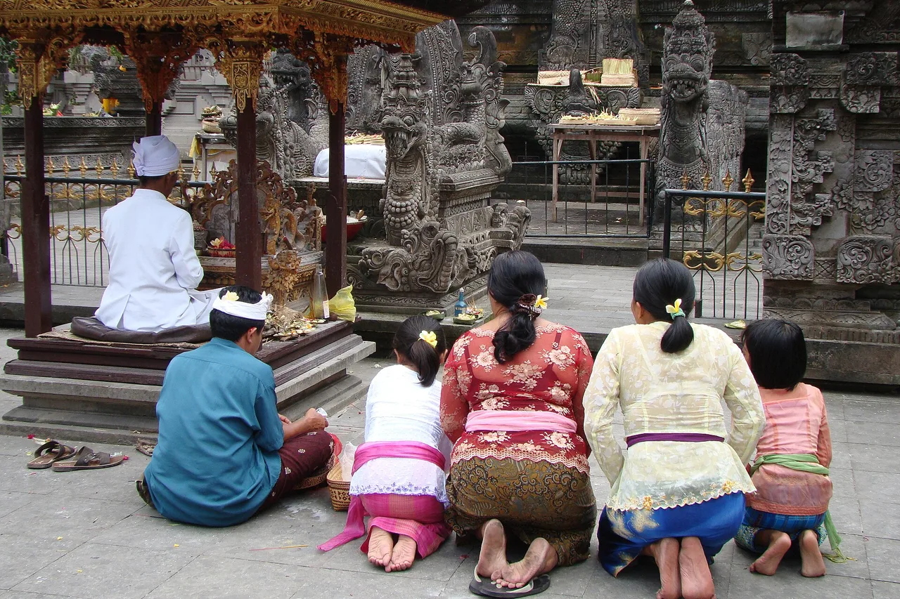 Fieles con ropa ceremonial sentados en el patio de un templo hindú, zona de Ubud, Bali