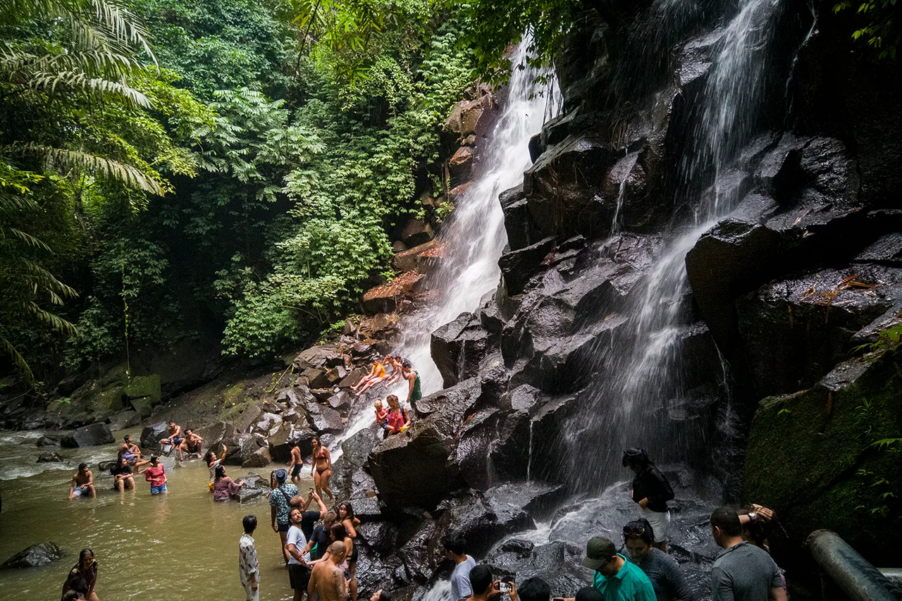 La cascata di Kanto Lampo che scivola su rocce nere a gradini, molti visitatori nella vasca