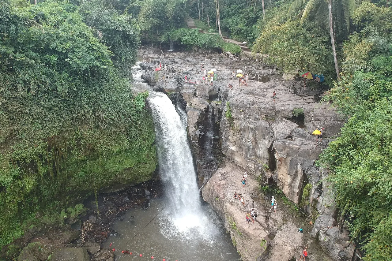 L’ampia cascata di Tegenungan vista dall’alto, visitatori sulle rocce piatte sottostanti, Bali