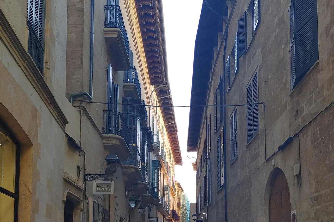 Un vicolo stretto di Palma con facciate in arenaria, passanti in lontananza
