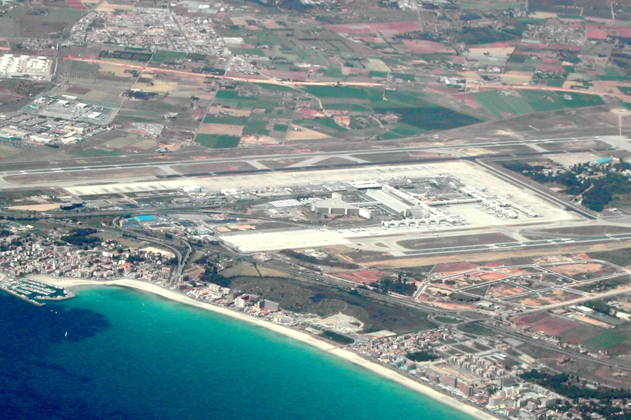 Vue aérienne de l’aéroport de Palma de Majorque avec ses pistes et son terminal, la côte aux eaux turquoise au premier plan