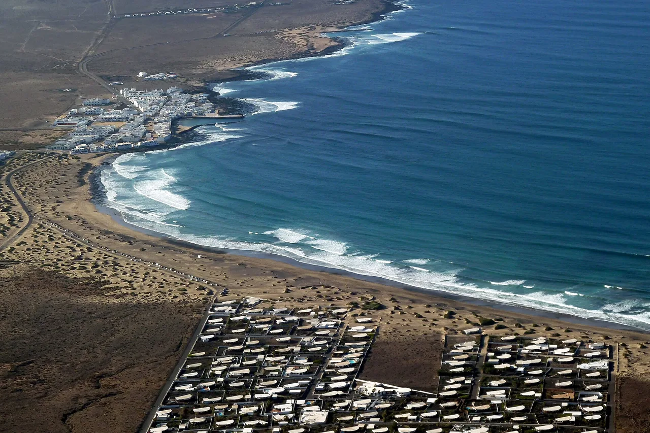 The long beach of Famara and its lines of surf, with the village of Caleta de Famara behind