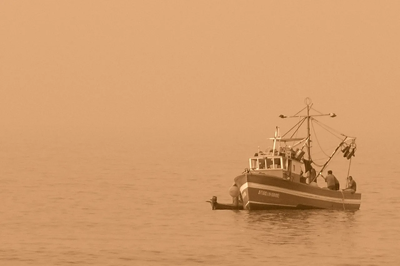 Horizon marin voilé par la calima : le soleil traverse à peine la poussière saharienne en suspension