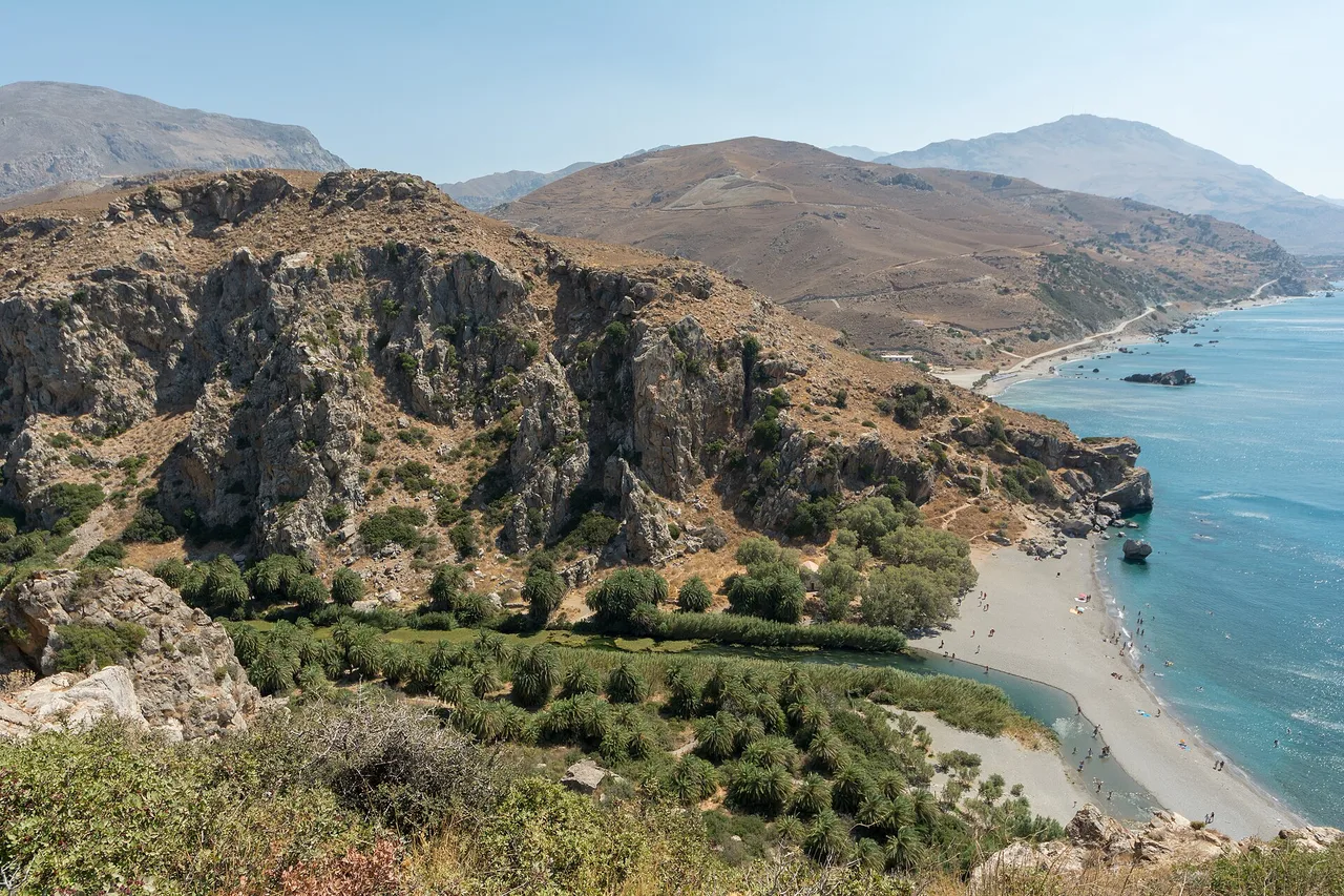 Vue plongeante sur la plage de palmiers de Preveli : la rivière serpente au milieu d’un épais bosquet de palmiers verts jusqu’au sable, puis se jette dans la mer de Libye d’un bleu profond.