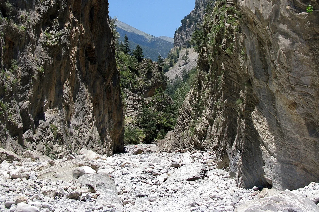 Les Portes de fer des gorges de Samaria : un passage étroit entre deux parois rocheuses verticales, avec une bande de ciel bleu tout en haut.
