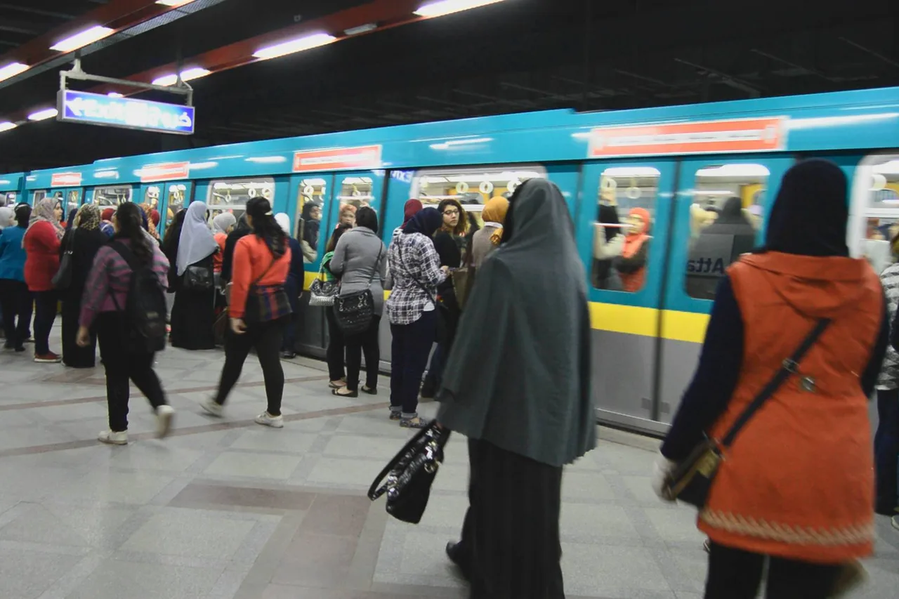 Un treno turchese della metropolitana del Cairo fermo al binario, passeggeri che salgono e scendono.
