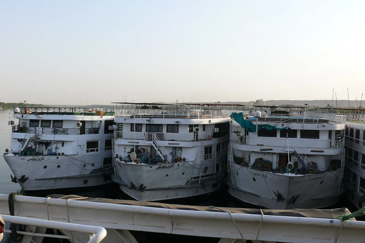 Plusieurs grands bateaux de croisière amarrés côte à côte contre la rive à Assouan.