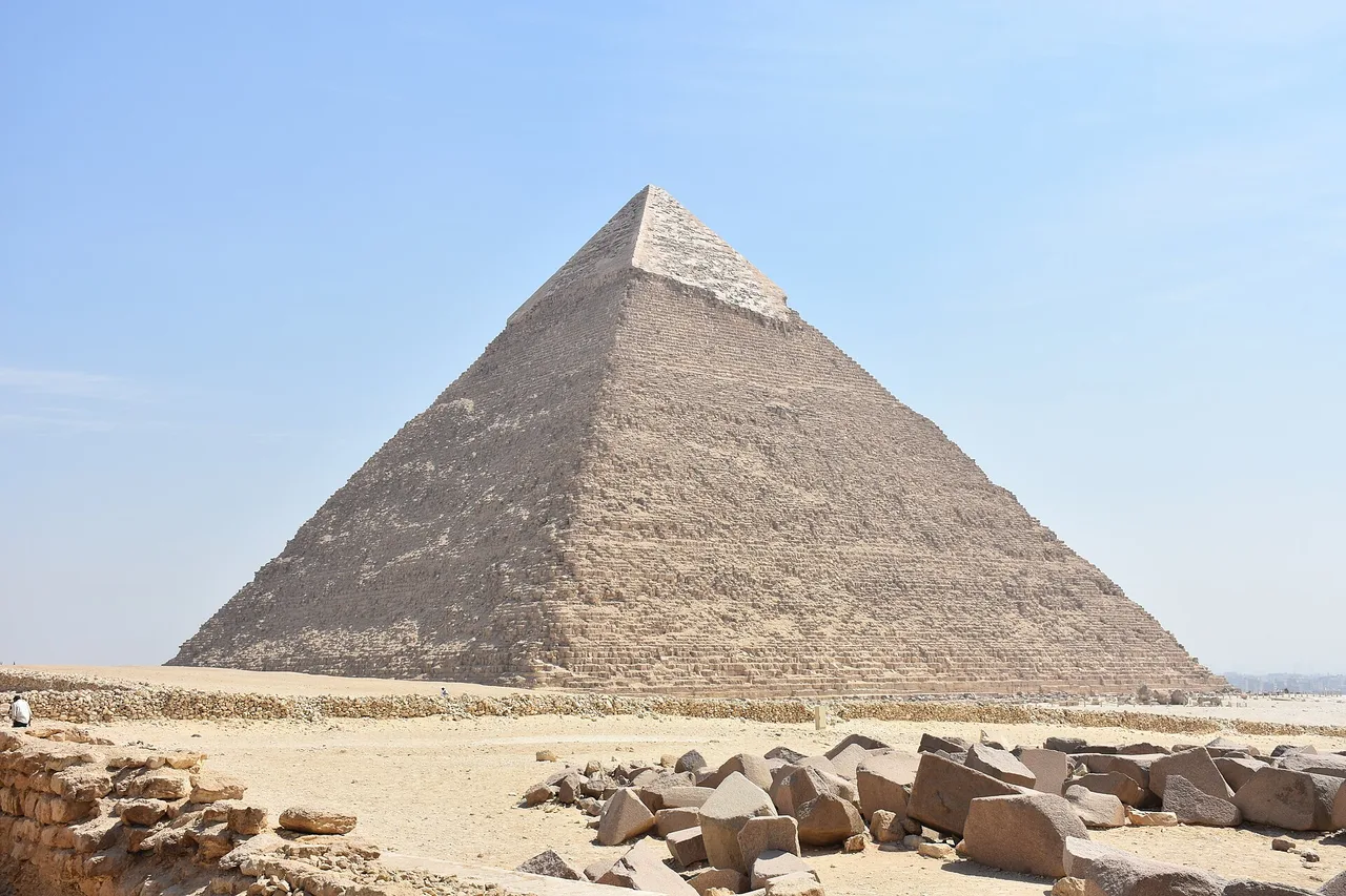 La pyramide de Khéphren avec les restes de son revêtement lisse au sommet, des blocs de pierre au premier plan.