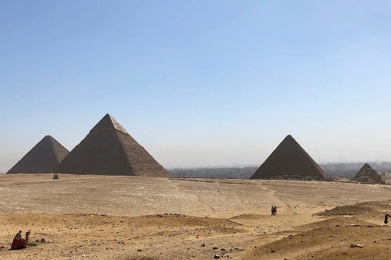 Vue sur le désert et les trois grandes pyramides de Gizeh, avec des pyramides secondaires plus petites.