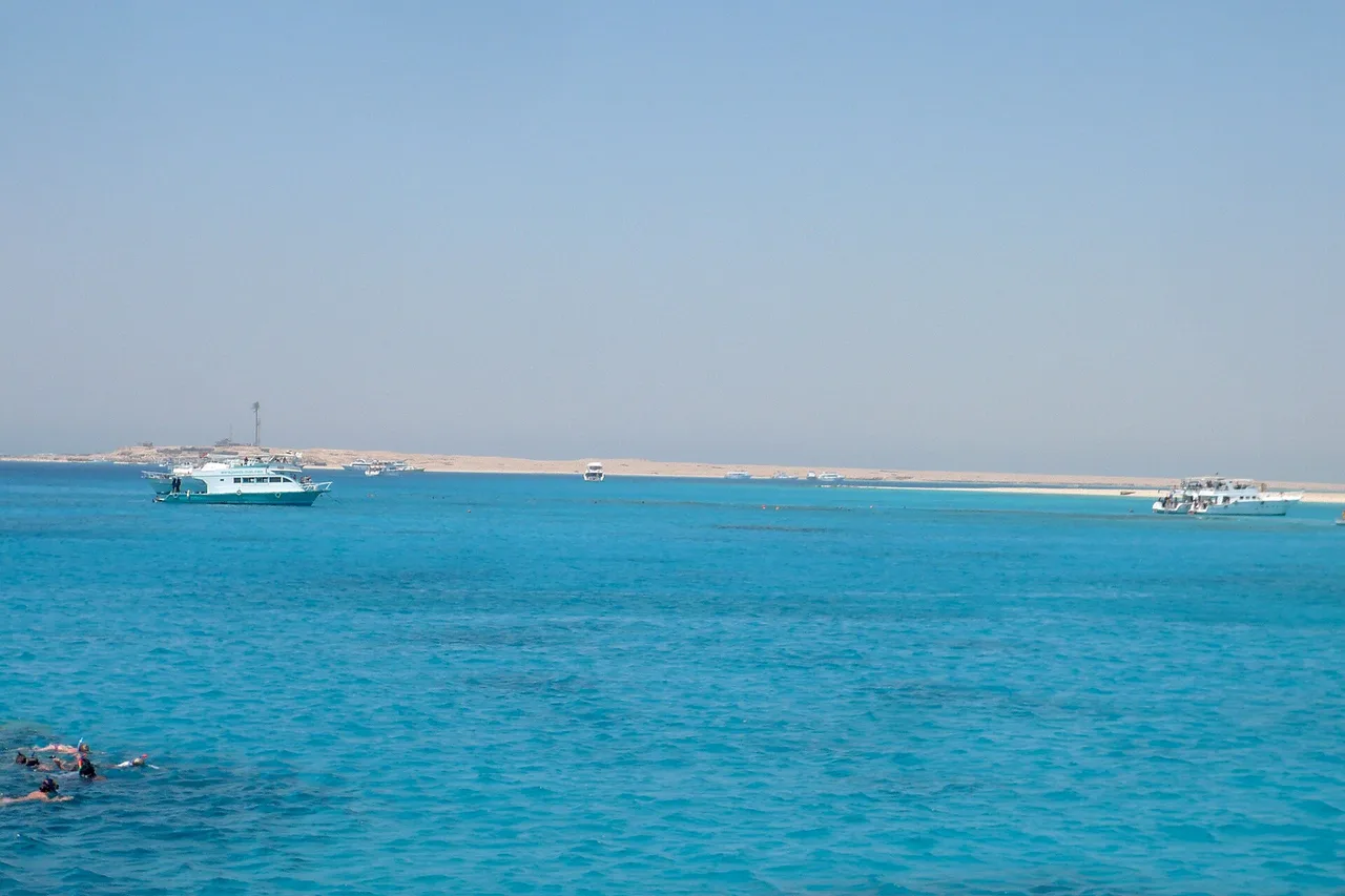 Türkisfarbenes Wasser vor der Insel Giftun bei Hurghada, mit Ausflugsbooten und einem Schnorchler im Vordergrund.