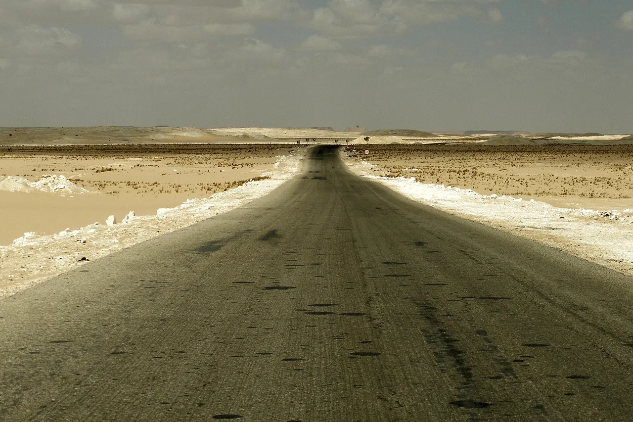 An empty tarmac road running through the White Desert in western Egypt.