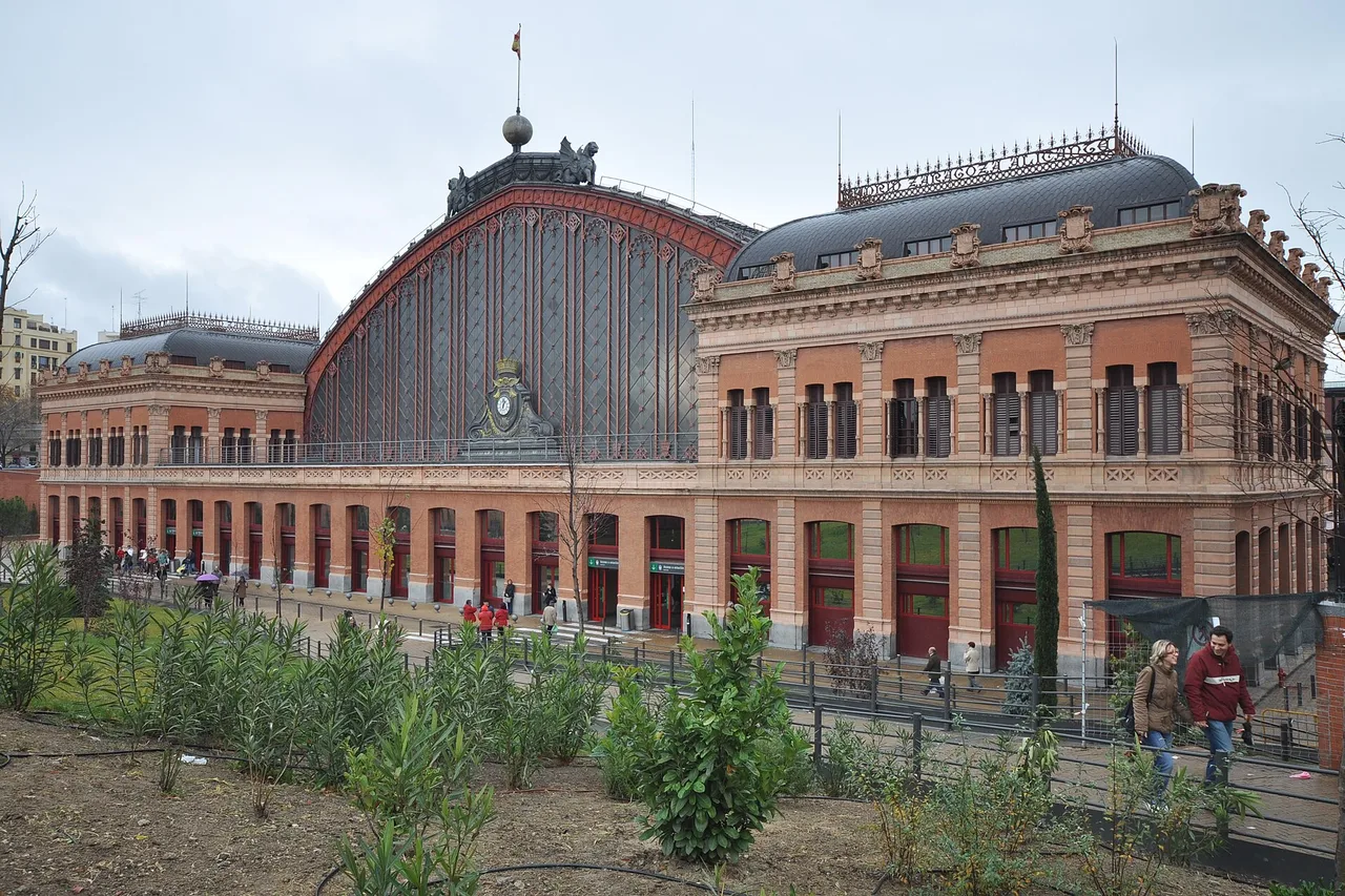 The brick façade and great glass vault of Madrid Puerta de Atocha station on a grey day