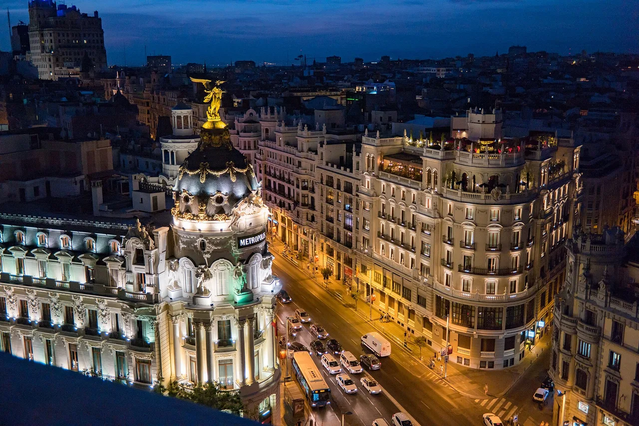 Madrid's Gran Vía lit at dusk, the Metropolis building in the foreground