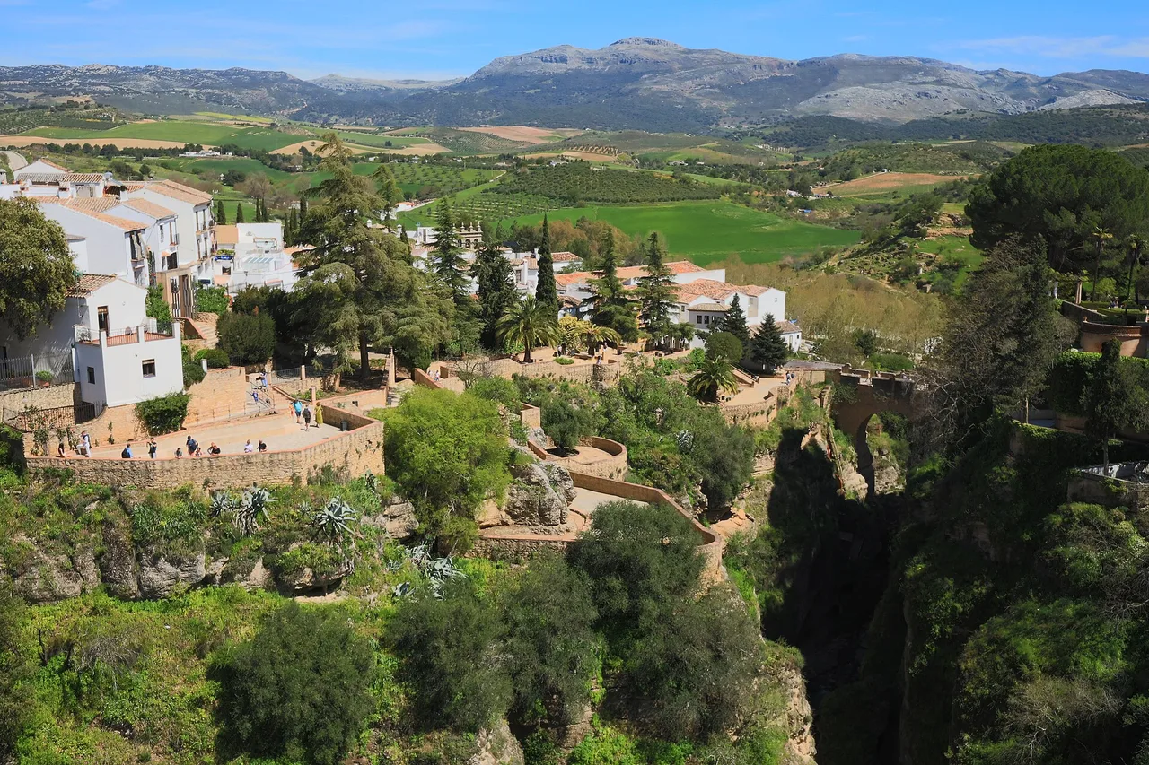 Ronda perched on the edge of its gorge, with green countryside and mountains behind