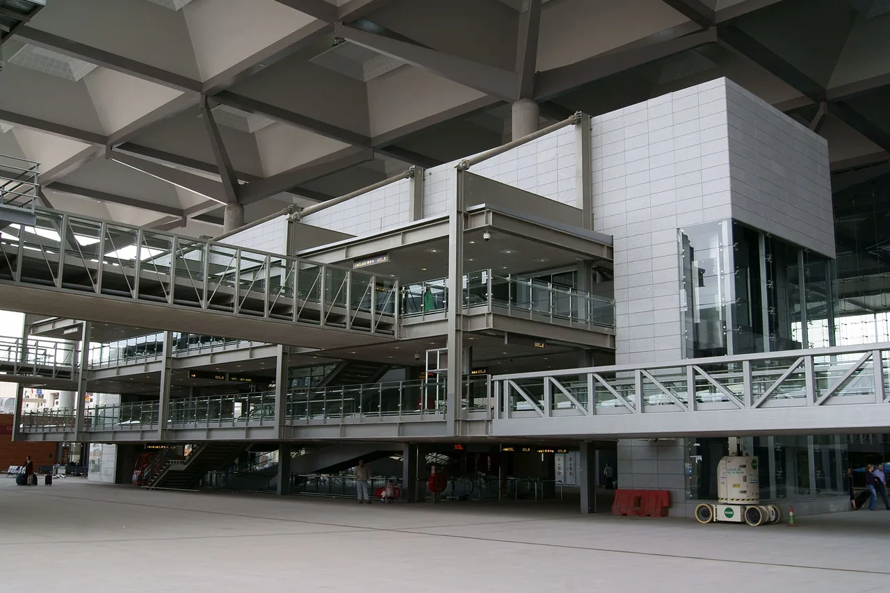 Der Verkehrsknoten am Flughafen Málaga: eine mehrstöckige Stahl-Glas-Konstruktion mit Stegen und Treppen unter einer Dachkonstruktion, davor ein weiter freier Platz
