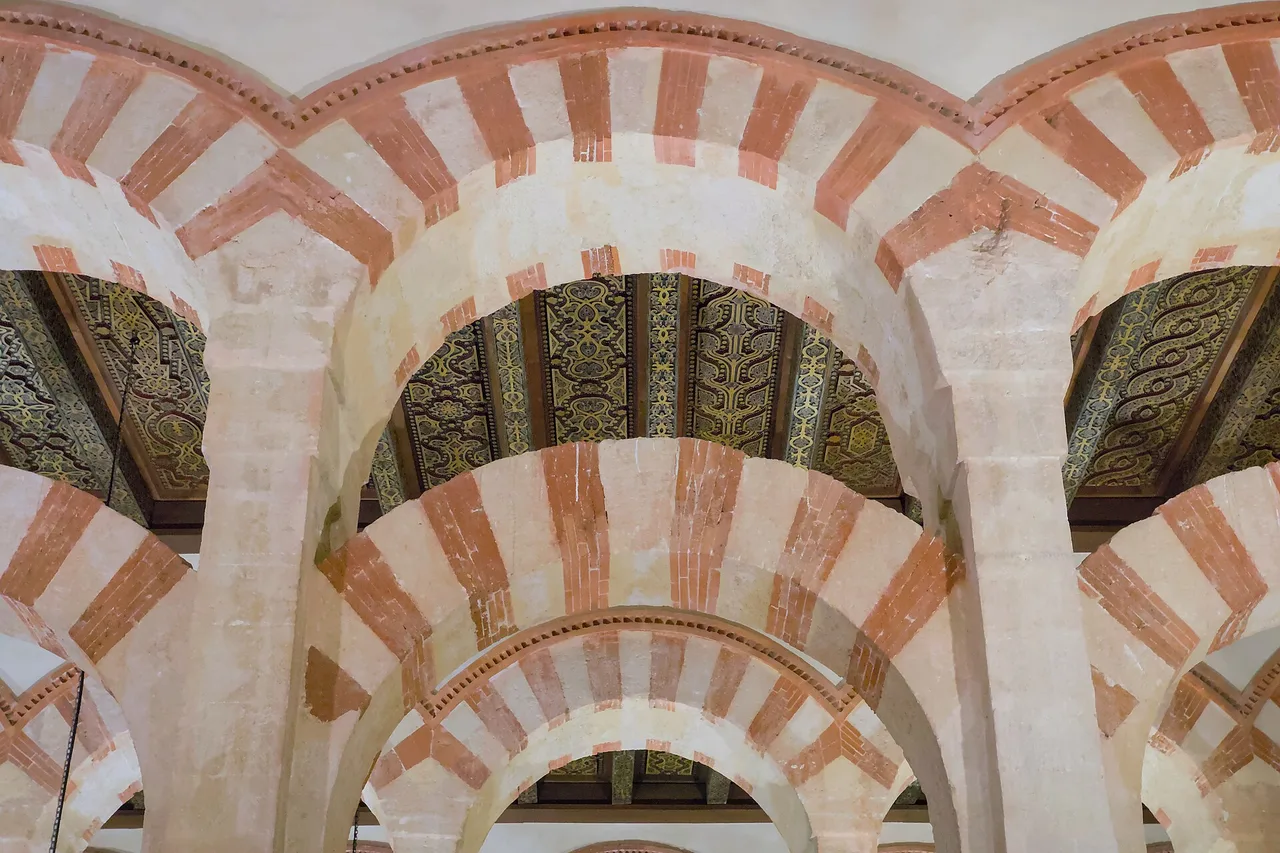 Des arcs en fer à cheval rayés de rouge et de blanc dans la salle de prière de la Mezquita-Catedral de Cordoue
