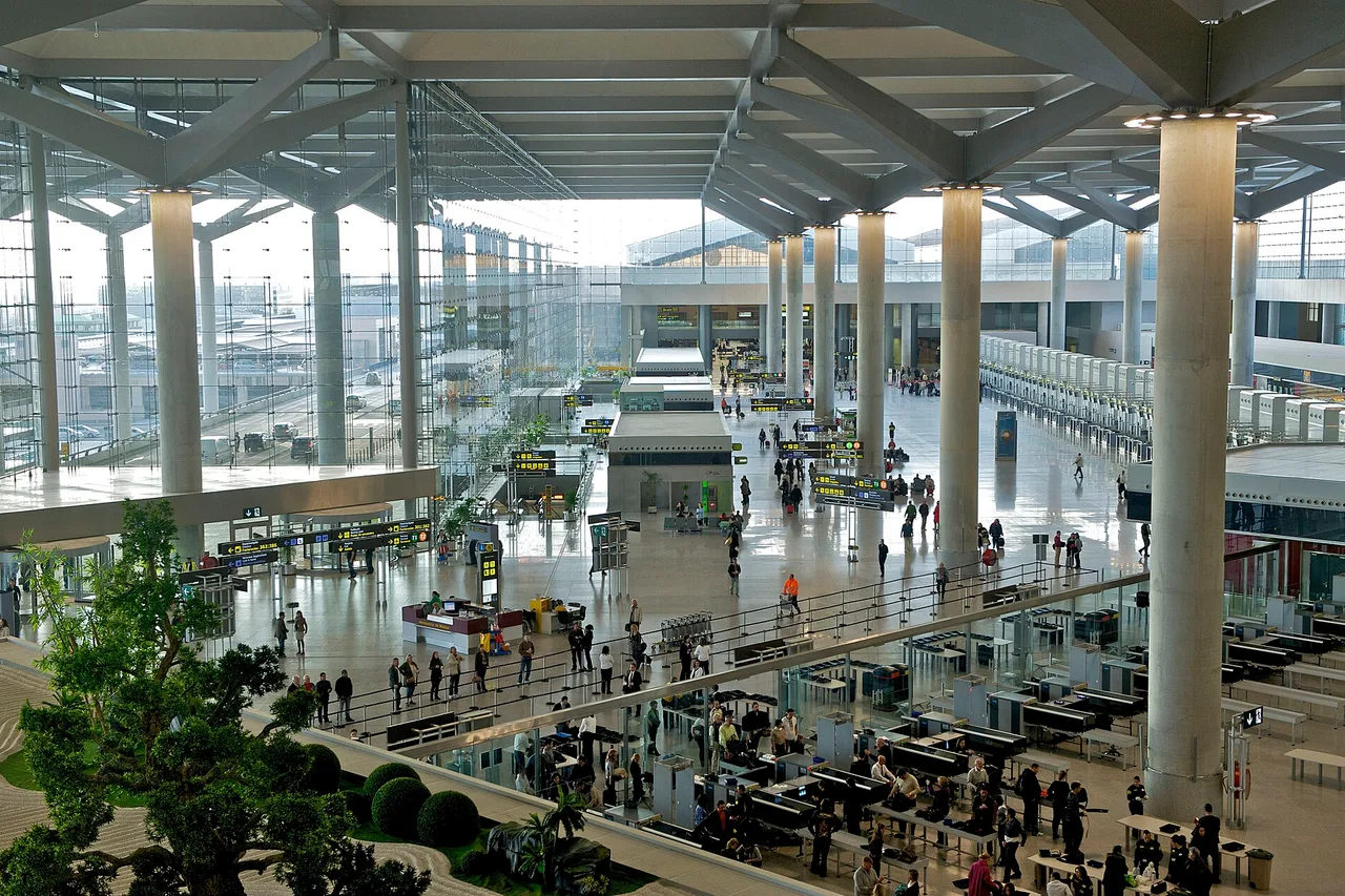 Hall du terminal 3 de l’aéroport de Málaga-Costa del Sol vu d’en haut, avec comptoirs d’enregistrement, piliers et voyageurs