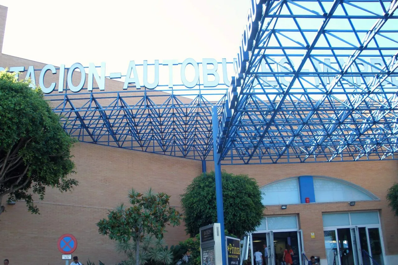 Entrée de la gare routière de Marbella, charpente métallique bleue, lettres « Estación de autobuses » et voyageurs sur les marches