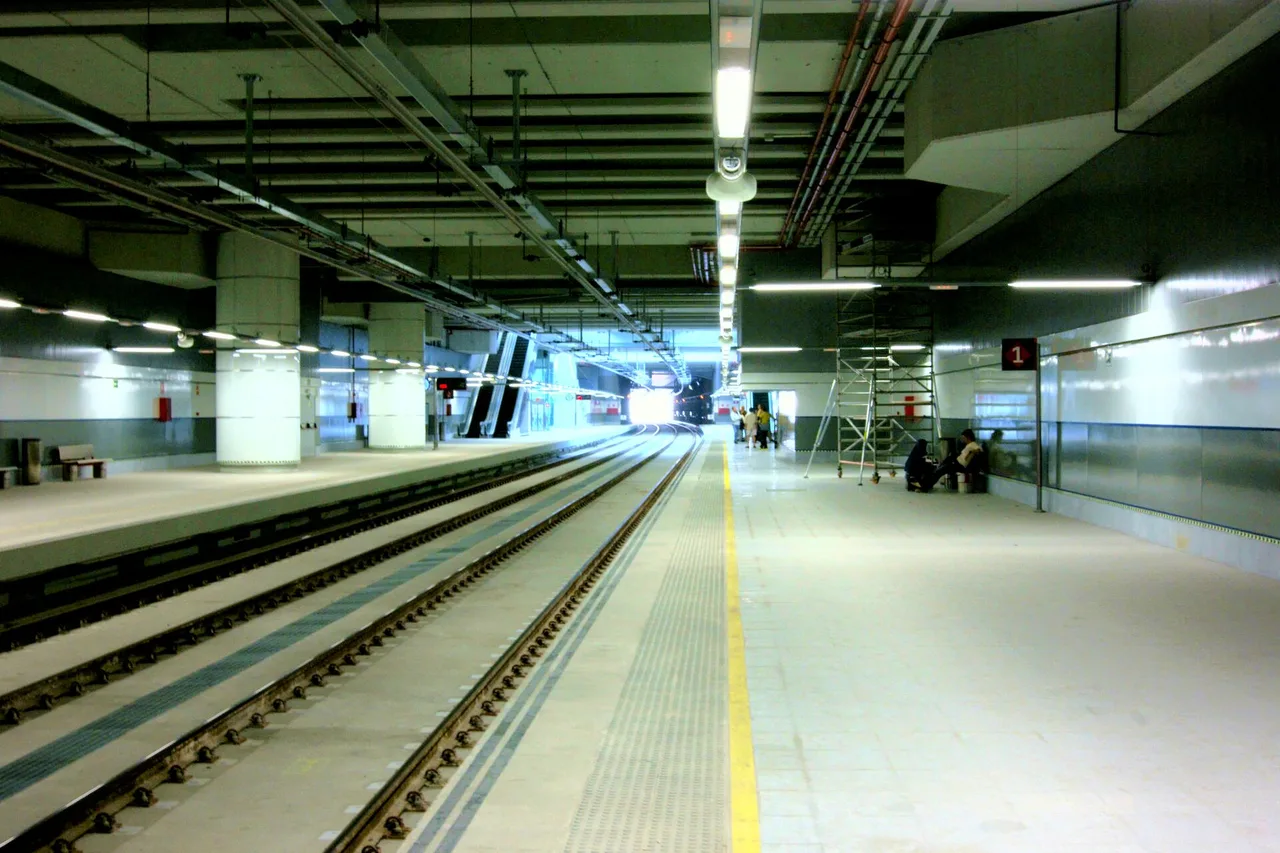 Quai de la gare souterraine de l’aéroport de Málaga, deux voies, escaliers mécaniques et quelques voyageurs