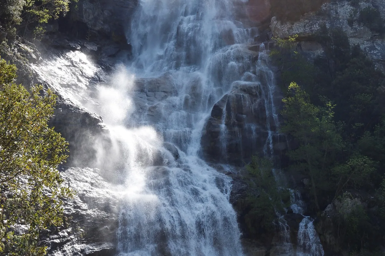 Una cascata scende su rocce scure circondata dal bosco, vicino a Bocognano in Corsica.