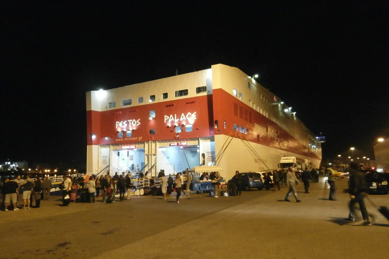 Des passagers à pied remontant la rampe d’un ferry à quai, le soir, dans un port grec
