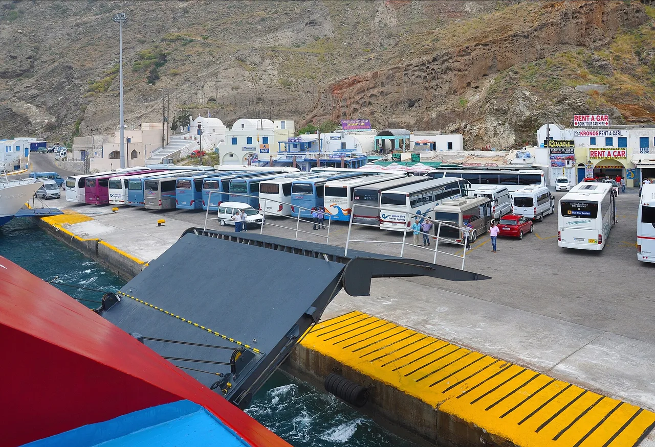 Le port d’Athinios à Santorin, une rampe de ferry ouverte et une file de bus et de navettes alignés au quai