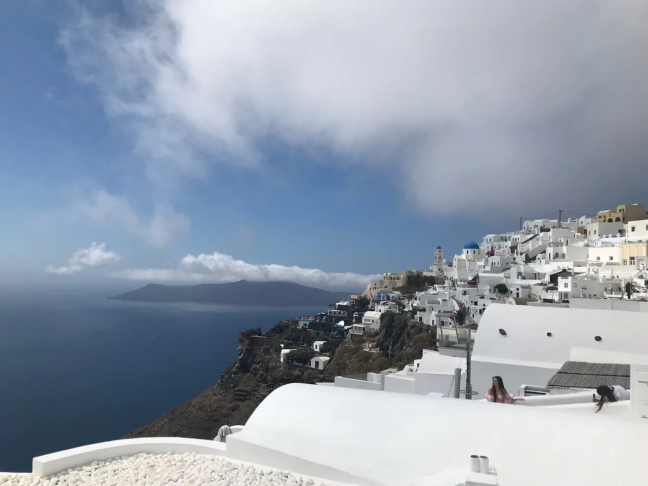 Les terrasses blanches d’Imerovigli au-dessus de la caldeira, avec le volcan dans la brume