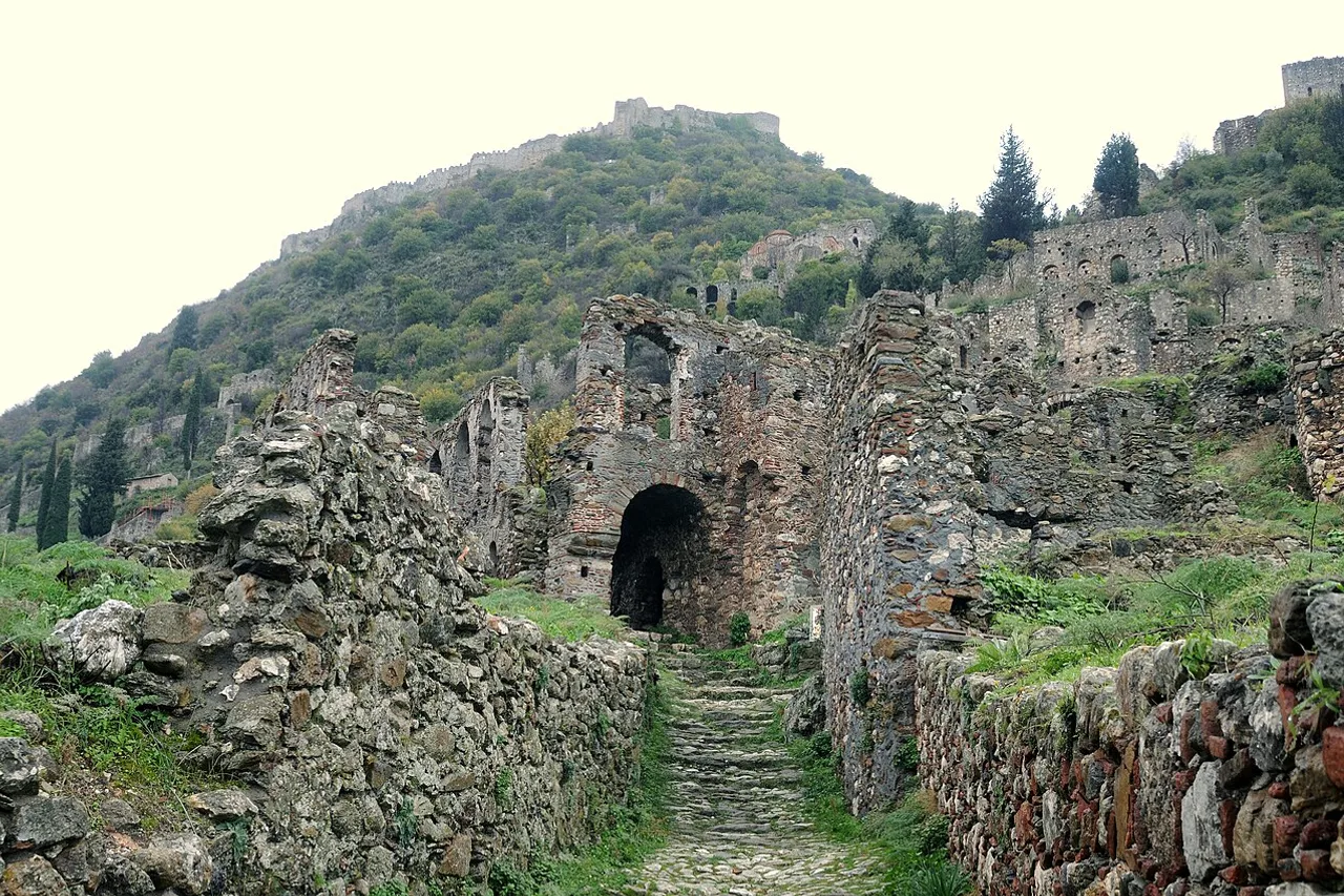 Ein gepflasterter Weg zwischen den byzantinischen Ruinen von Mystras, oben die Festung