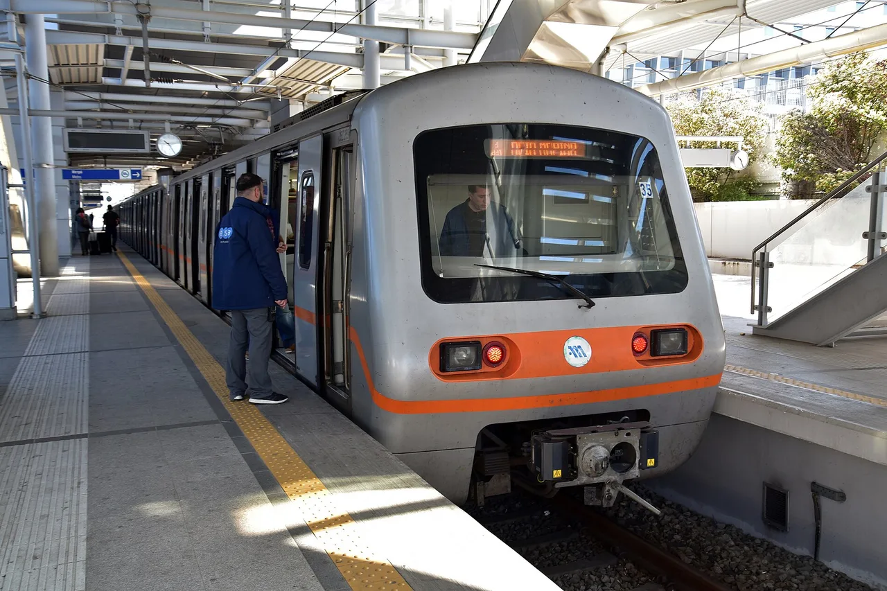 Metrozug der Linie 3 an einem Bahnsteig des Flughafens Athen, ein Mitarbeiter in blauer Jacke steht neben der offenen Tür