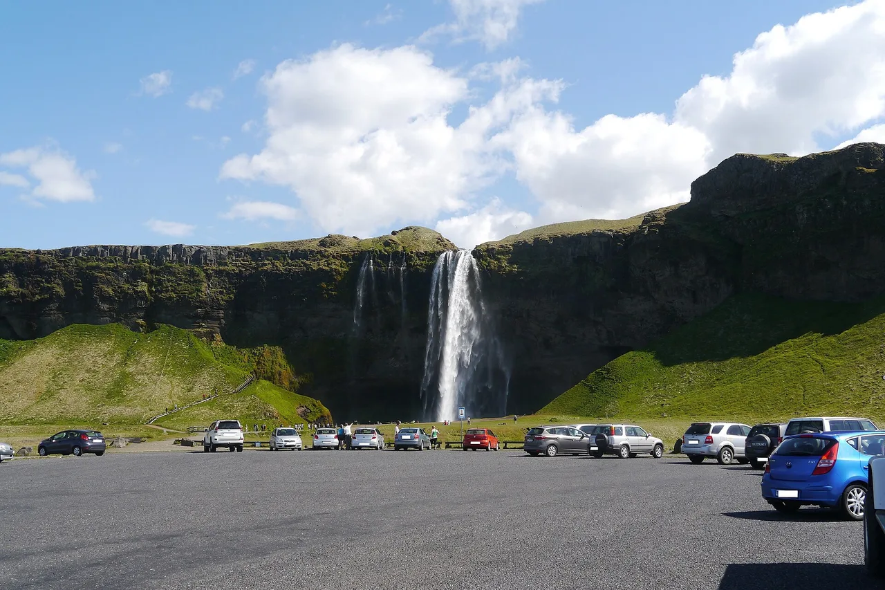 Car park full of cars at the foot of Seljalandsfoss waterfall