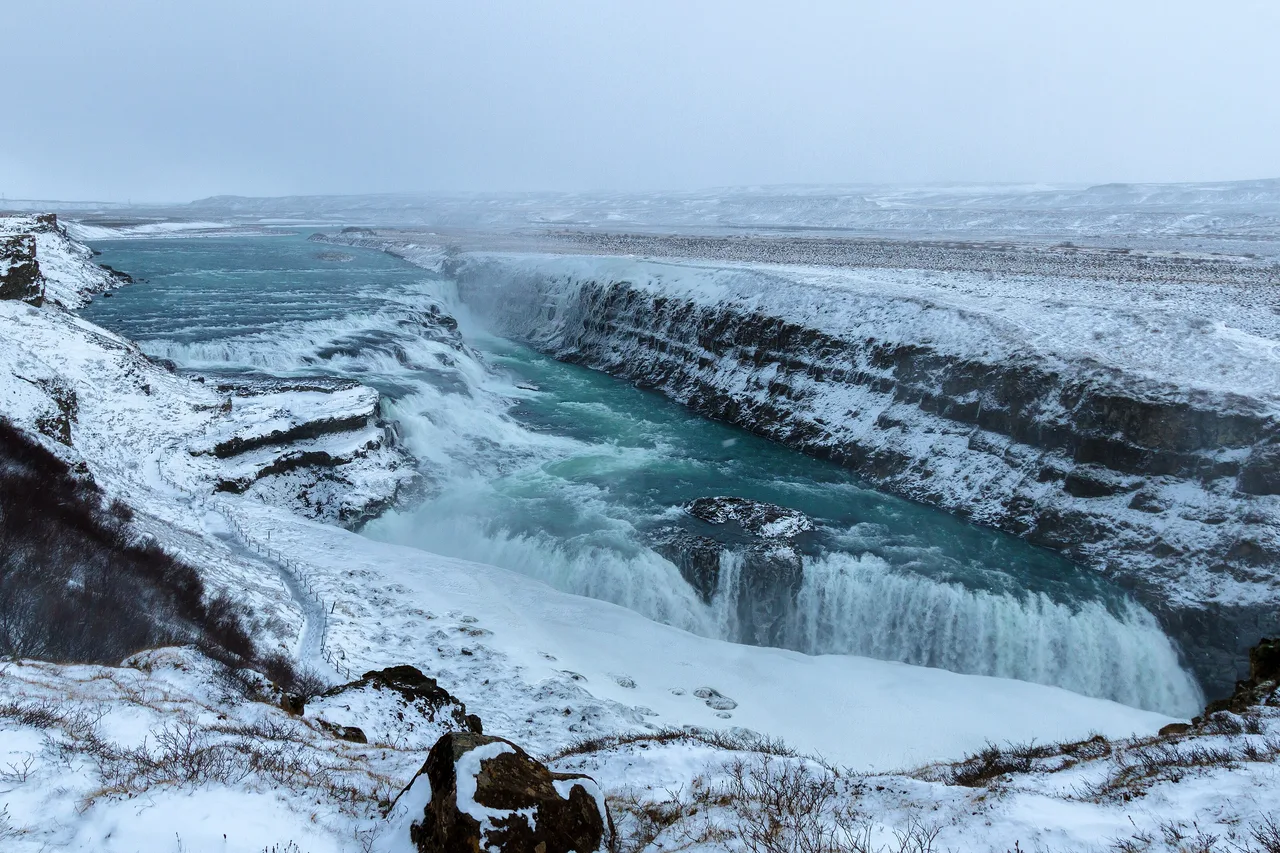Gullfoss im Februar, verschneite Schlucht und türkisfarbenes Wasser zwischen Eisplatten