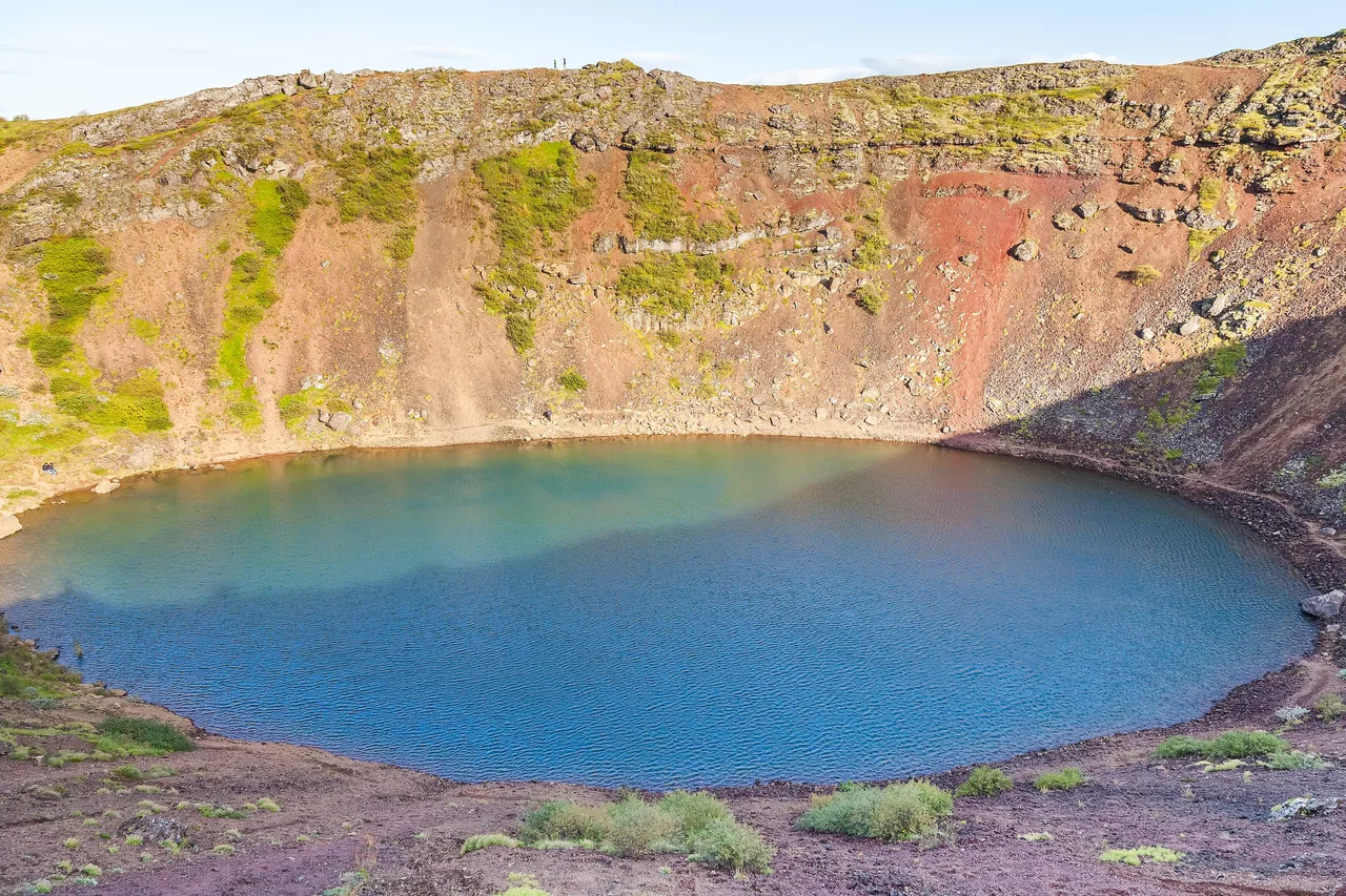 Der Krater Kerið mit türkisfarbenem See, umgeben von roter Schlacke