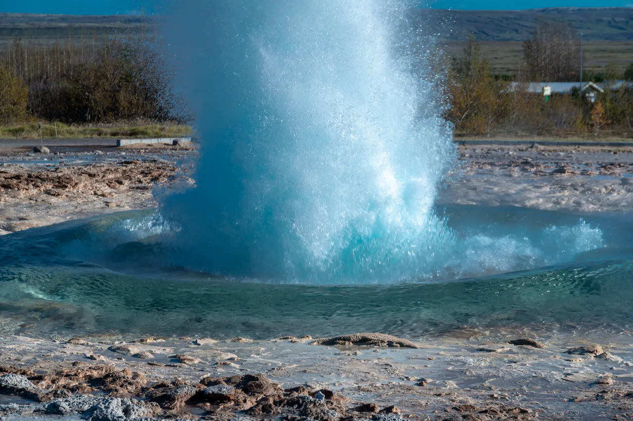 Die blaue Kuppel des Geysirs Strokkur im genauen Moment des Ausbruchs