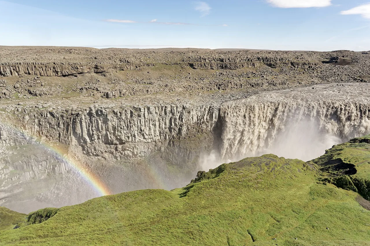 Der Wasserfall Dettifoss in seiner Schlucht, mit einem Regenbogen in der Gischt