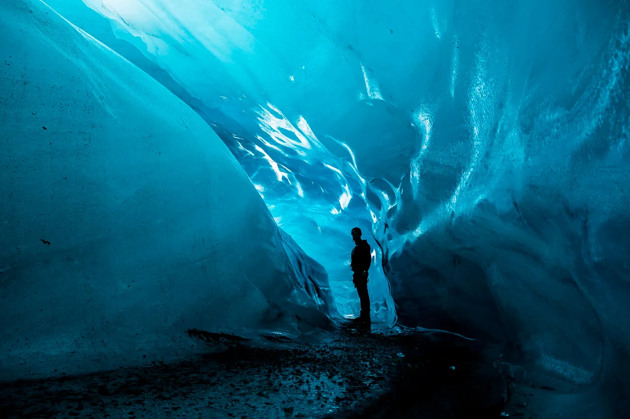 Silhouette einer Person in einer blauen Eishöhle unter einem isländischen Gletscher