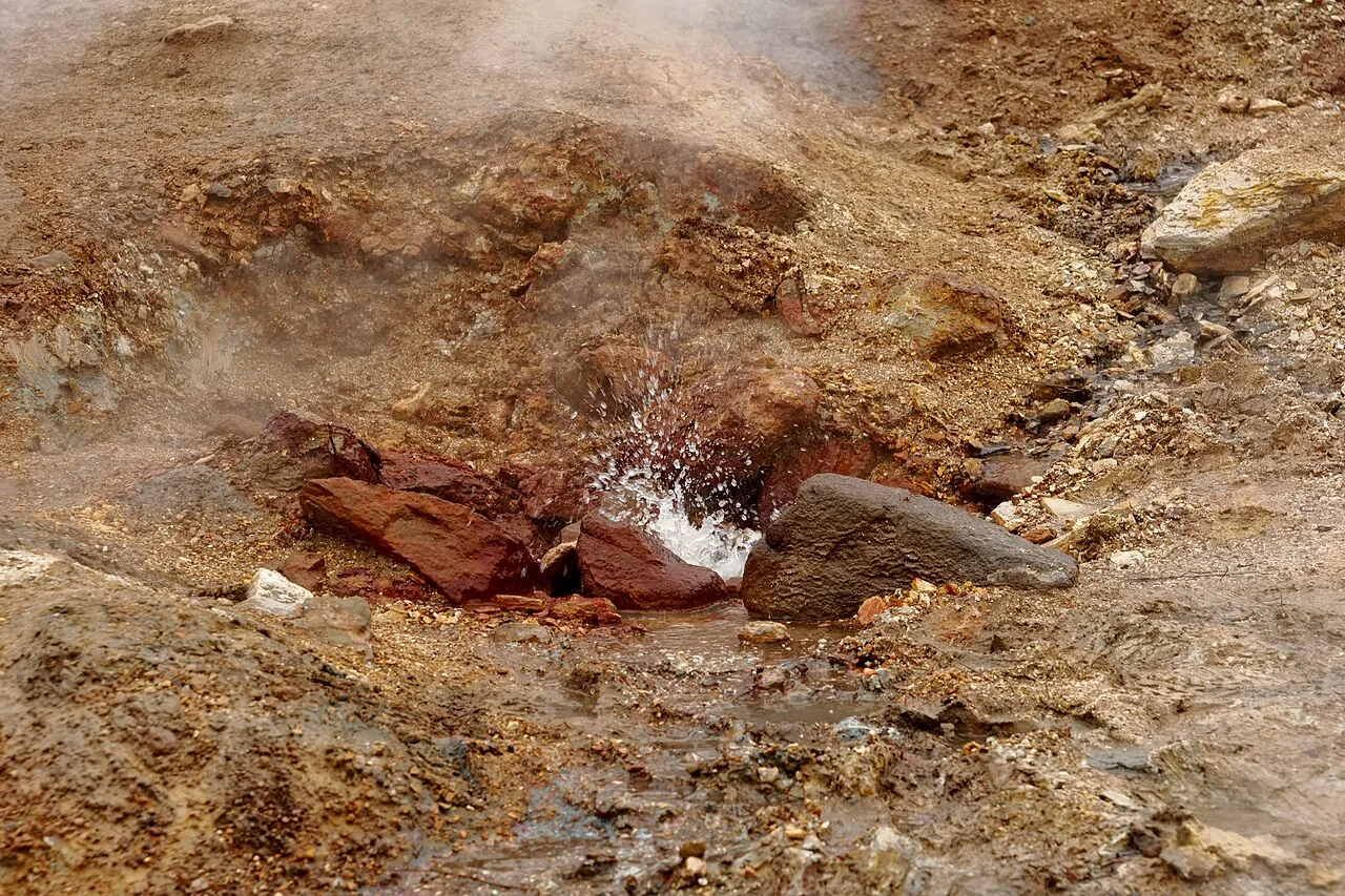 Kochende Quelle ebenerdig in einer Mulde aus rotem und ockerfarbenem Boden