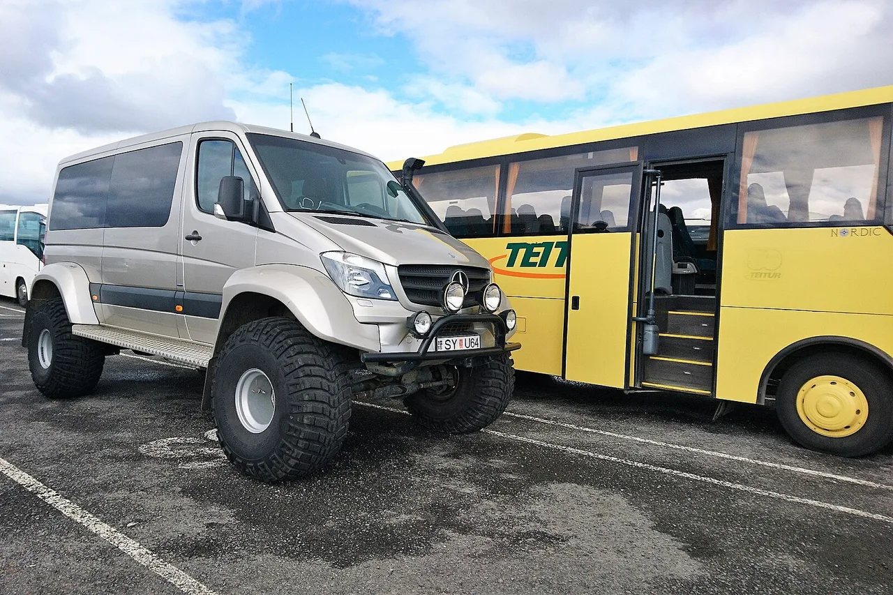Höhergelegter Mercedes-Sprinter-4×4-Camper neben einem gelben Geländebus in Island
