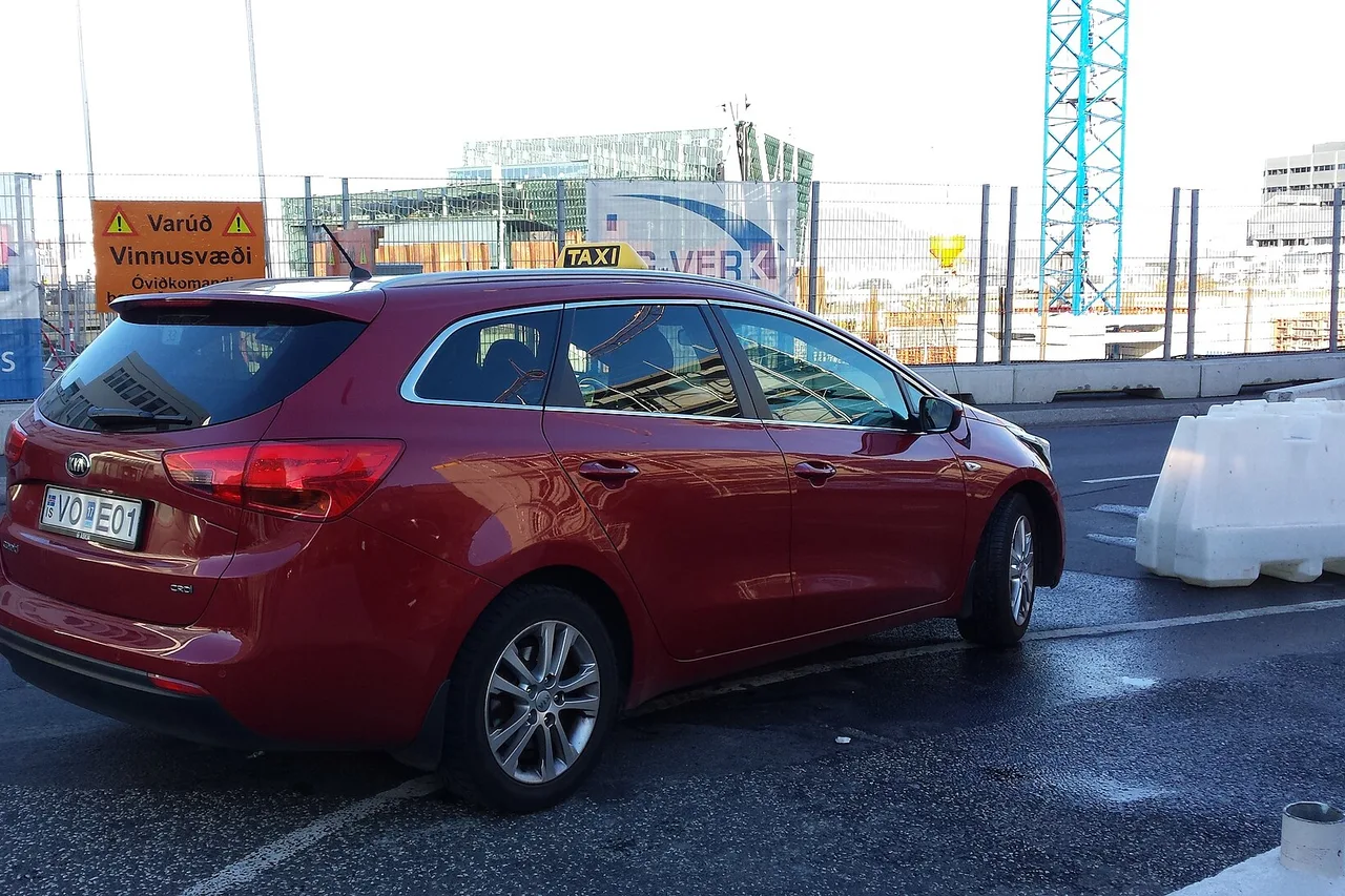 Break rouge équipé d’un lanterneau jaune TAXI dans une rue de Reykjavik, avec un chantier derrière