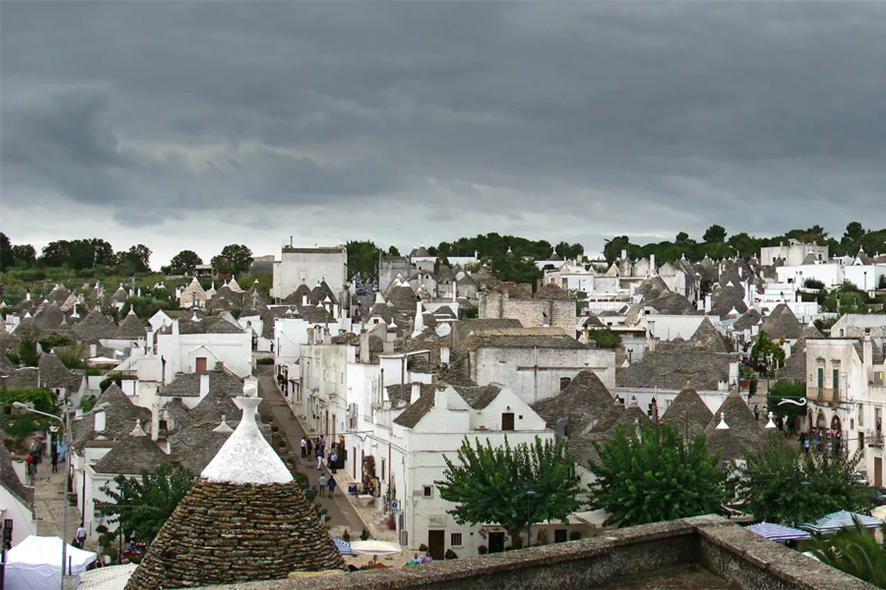 Des maisons blanches aux toits coniques en pierre grise, les trulli, à Alberobello, dans les Pouilles, sous des nuages sombres