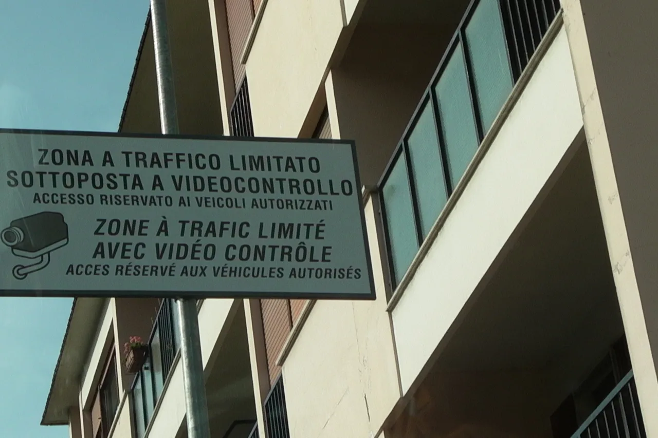 Un panneau fixé sur la façade d’un immeuble, portant la mention « Zona a traffico limitato sottoposta a videocontrollo » et le dessin d’une caméra, avec le même texte en français en dessous