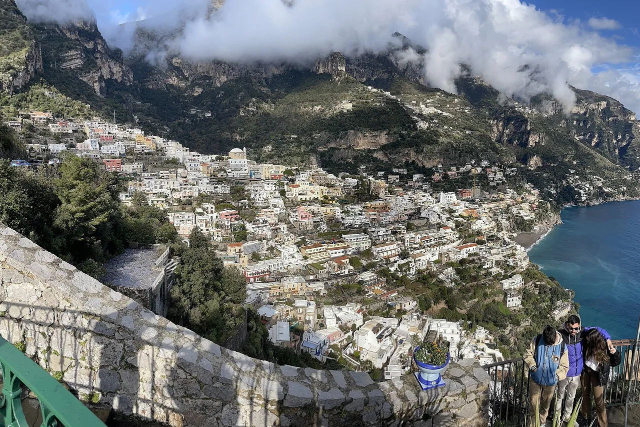 Positano on the Amalfi Coast: terraced houses on a steep slope, the sea behind and clouds over the mountains