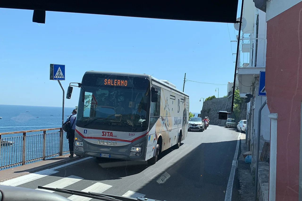 A SITA bus marked Salerno on the narrow coastal road of the Amalfi Coast, the sea on the left