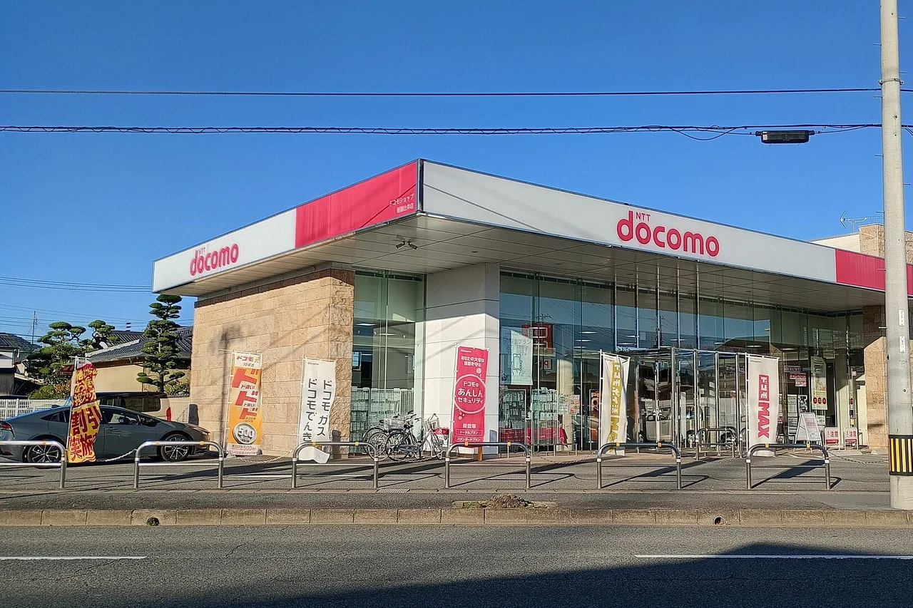 Boutique NTT docomo au Japon, façade rouge et blanche, banderoles devant l’entrée et parking