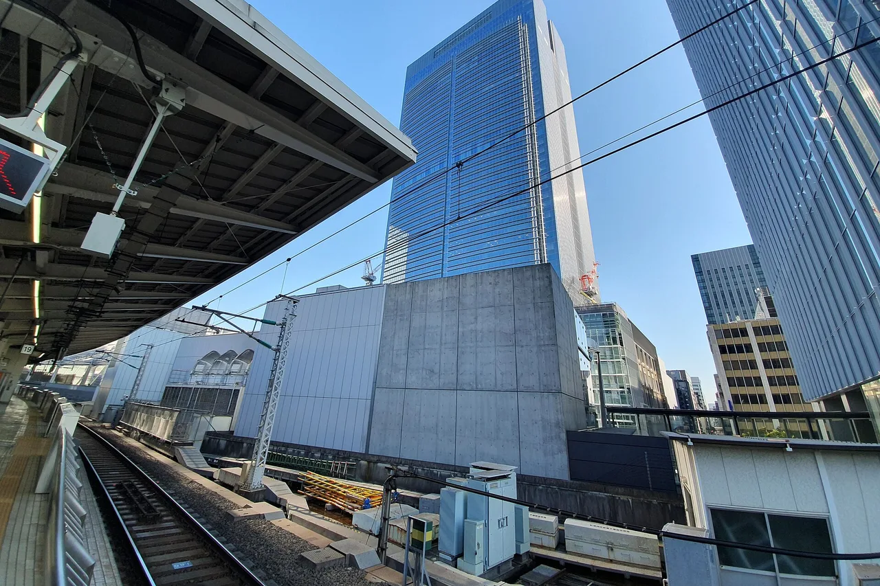 Bout de quai dans une gare de Tokyo, voies, caténaires et tours de verre en arrière-plan