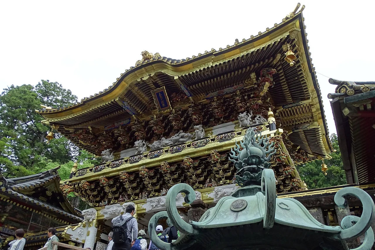 La porte Yomeimon du sanctuaire Toshogu à Nikko, aux sculptures dorées, avec un ornement de toit en bronze au premier plan