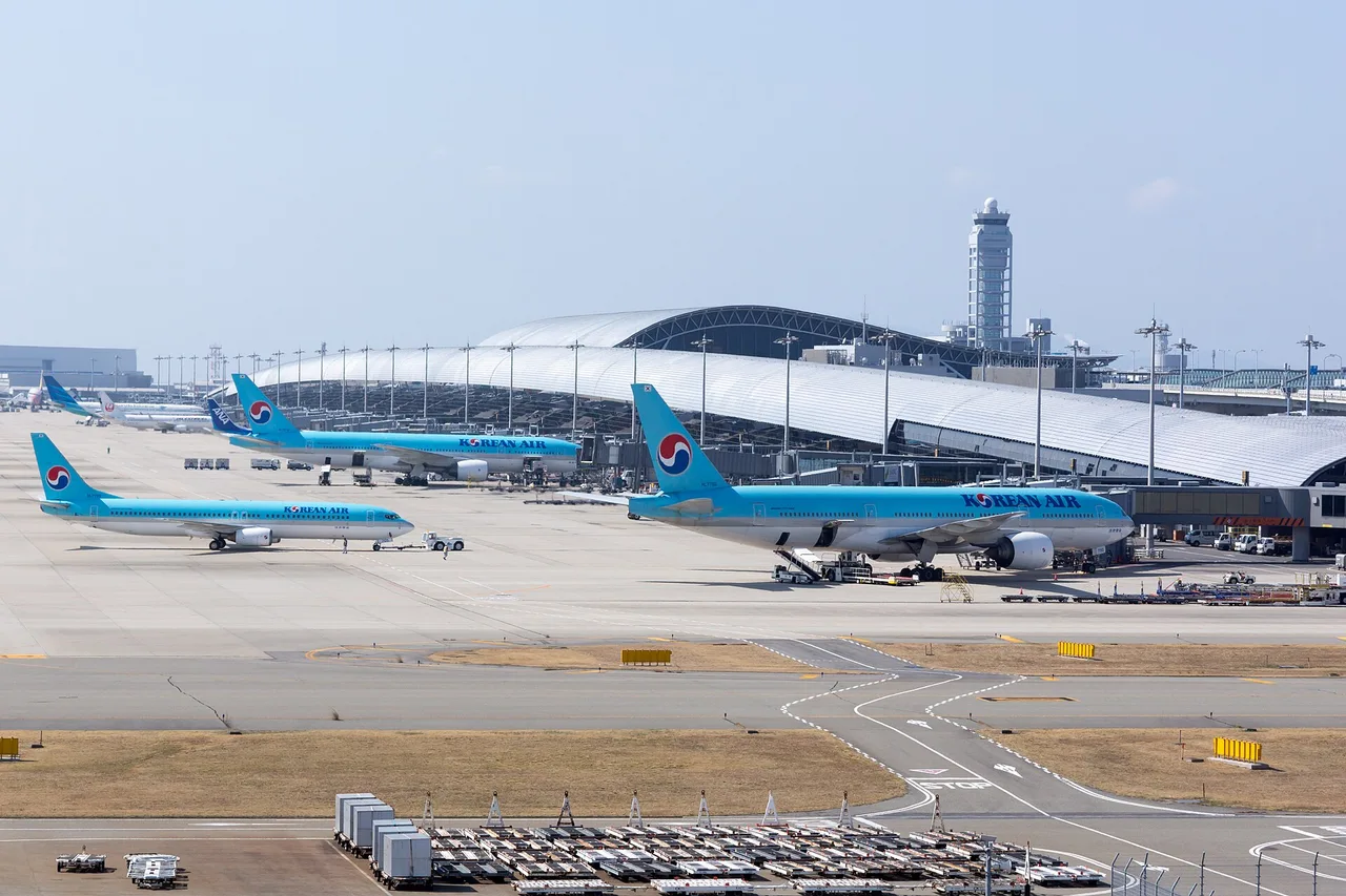 Flugzeuge von Korean Air auf dem Vorfeld des Flughafens Kansai vor dem langen, gewölbten Terminal und dem Kontrollturm
