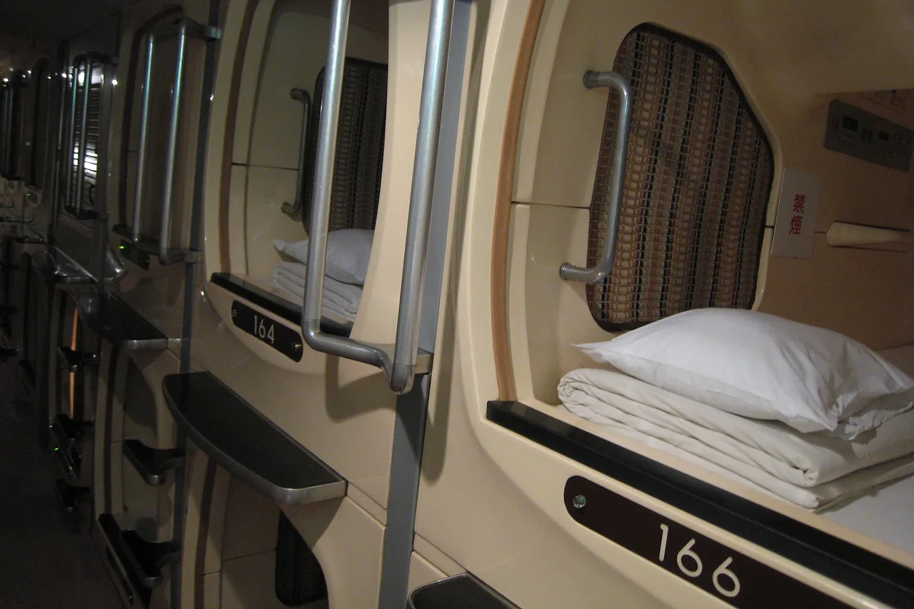 Fila di capsule in un capsule hotel giapponese, cuscini bianchi e numeri delle cuccette