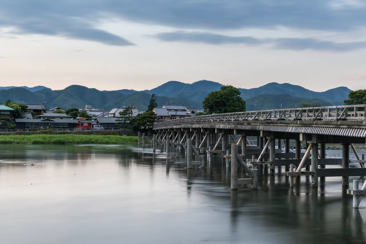 Ponte di legno Togetsukyō al crepuscolo sul fiume, colline di Arashiyama sullo sfondo